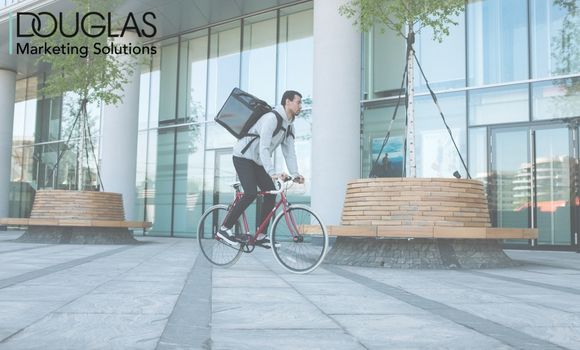 Mann auf Fahrrad mit Liefertasche auf dem Rücken